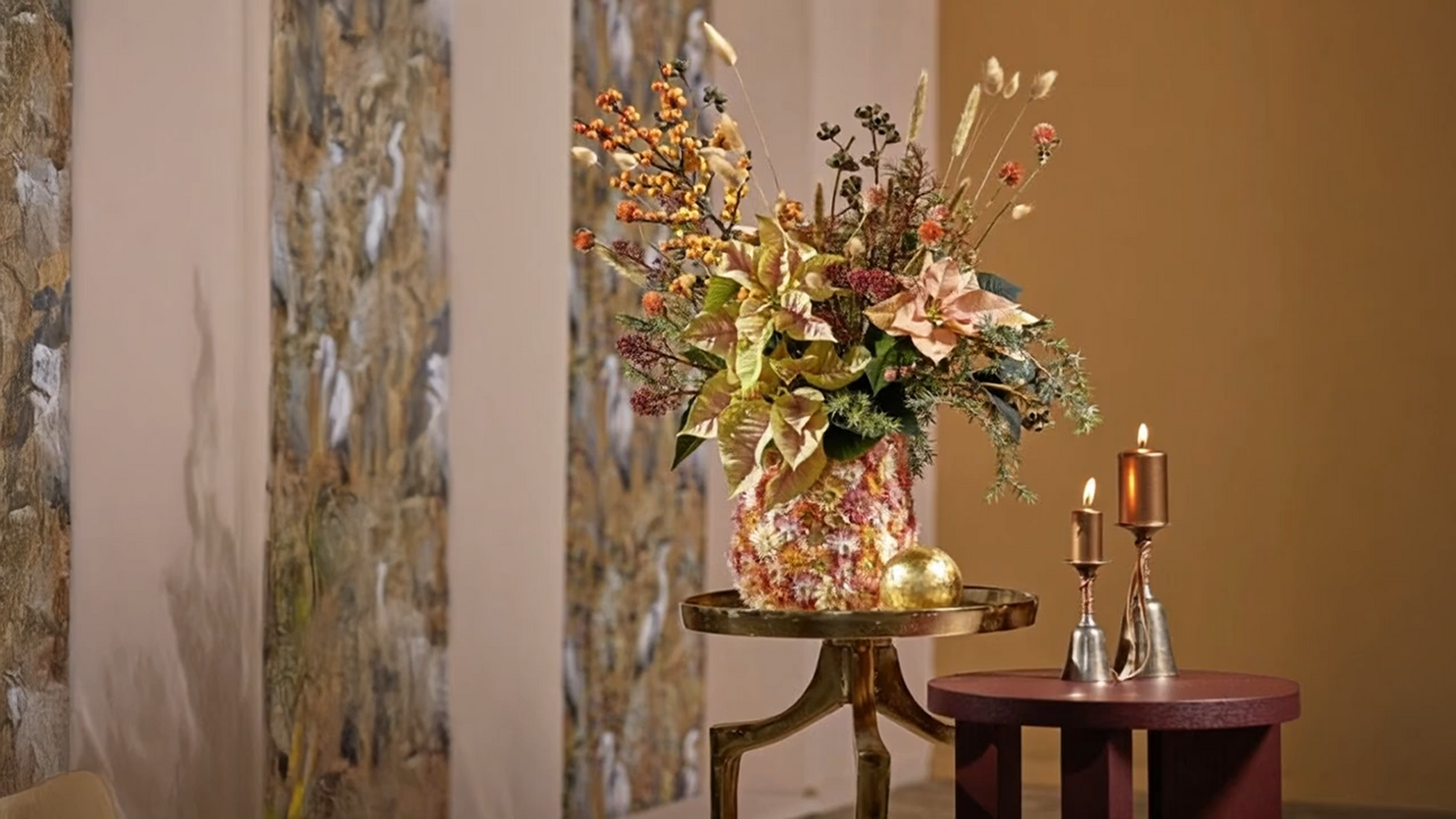 Table with a bouquet of flowers and candles next to sheer curtains in a warm room