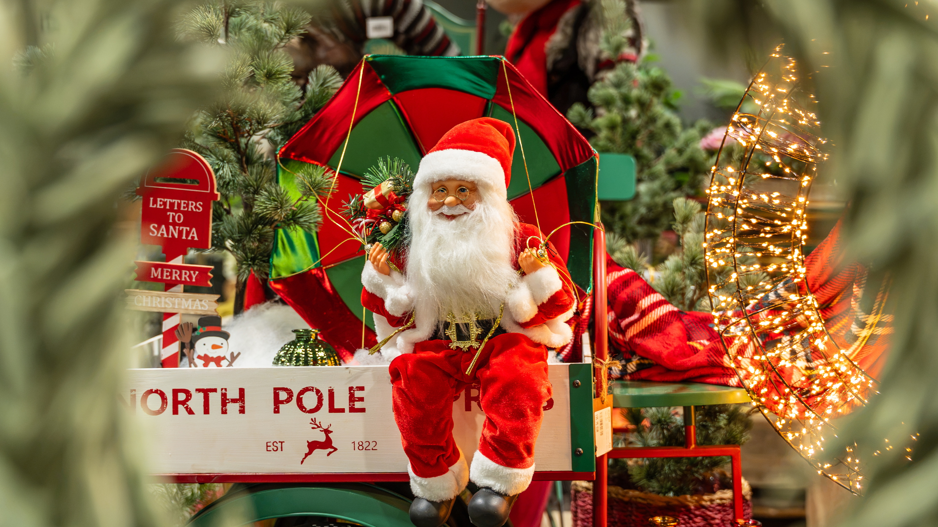 Santa Claus in a decorated North Pole sleigh with Christmas tree lights in the snow