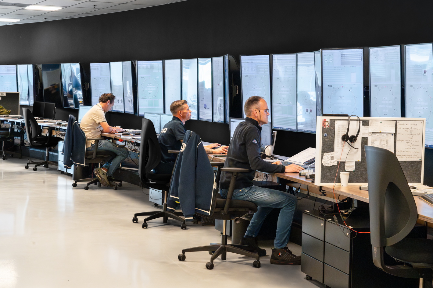 Des personnes travaillent sur des ordinateurs dans un bureau moderne avec de grandes fenêtres et une vue sur l’extérieur