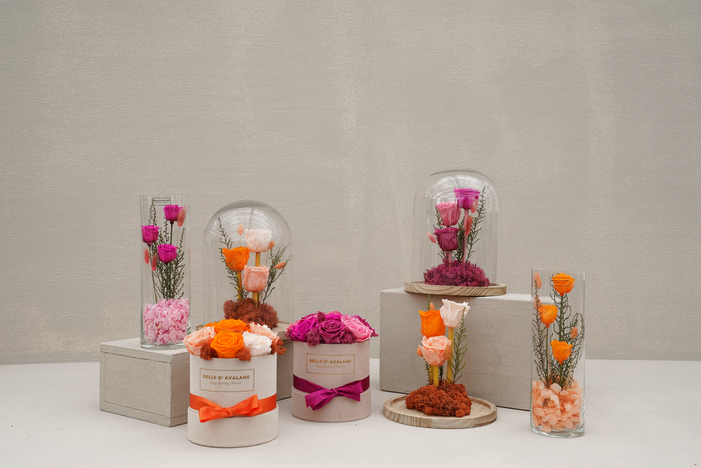 Decoratieve opstelling met glazen potten en roze-oranje bloemen op witte blokken