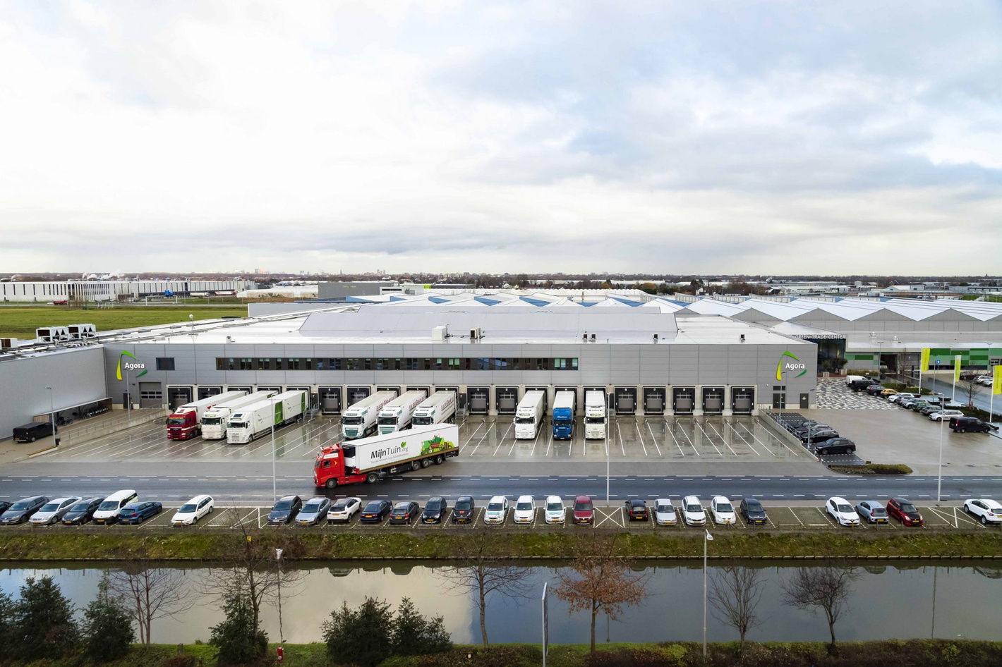 Photo aérienne d’un centre de distribution avec quais de chargement, camions et parking au bord de l’eau