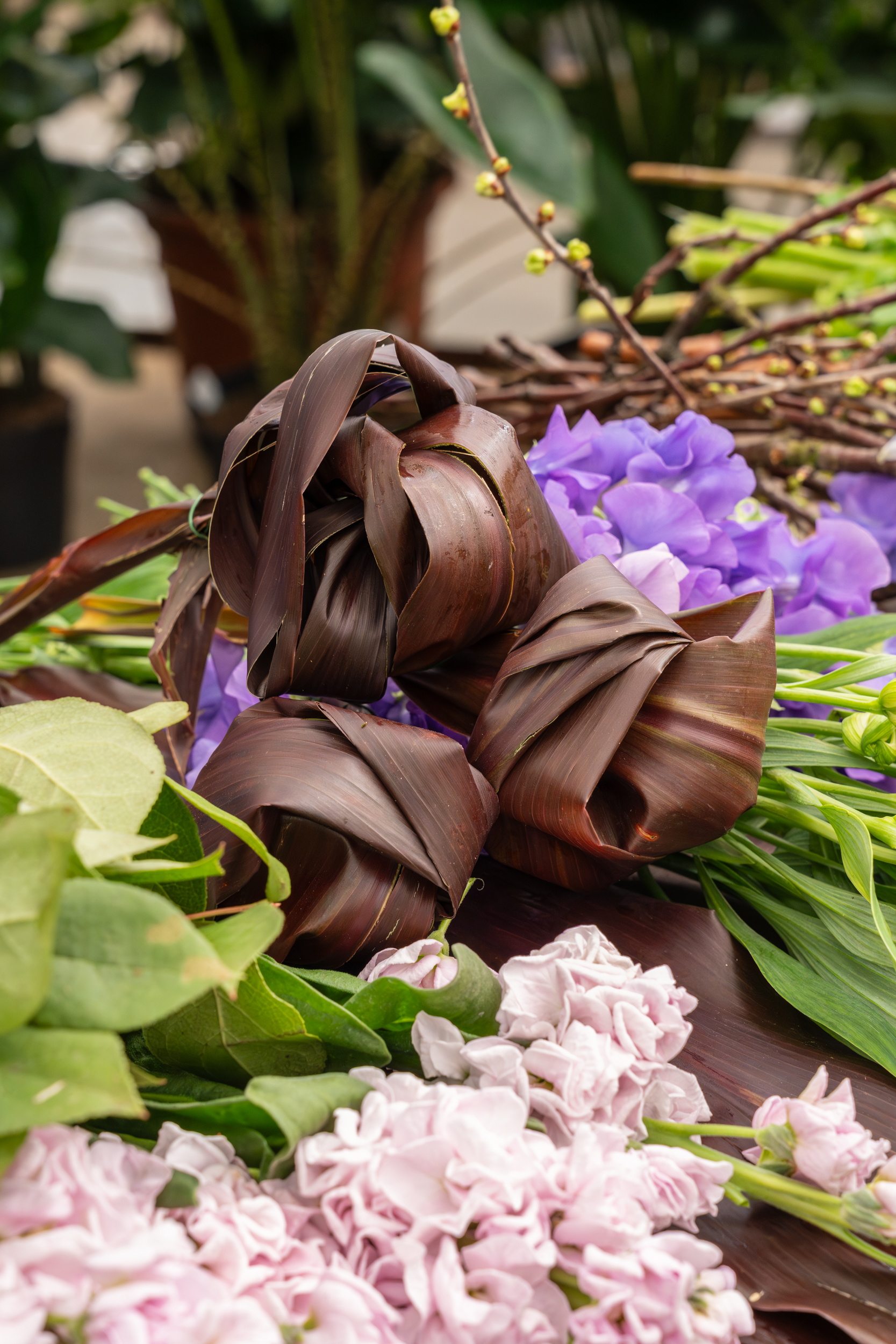 Bloemstuk met paarse en roze bloemen en donkerbruine bladeren op tafel