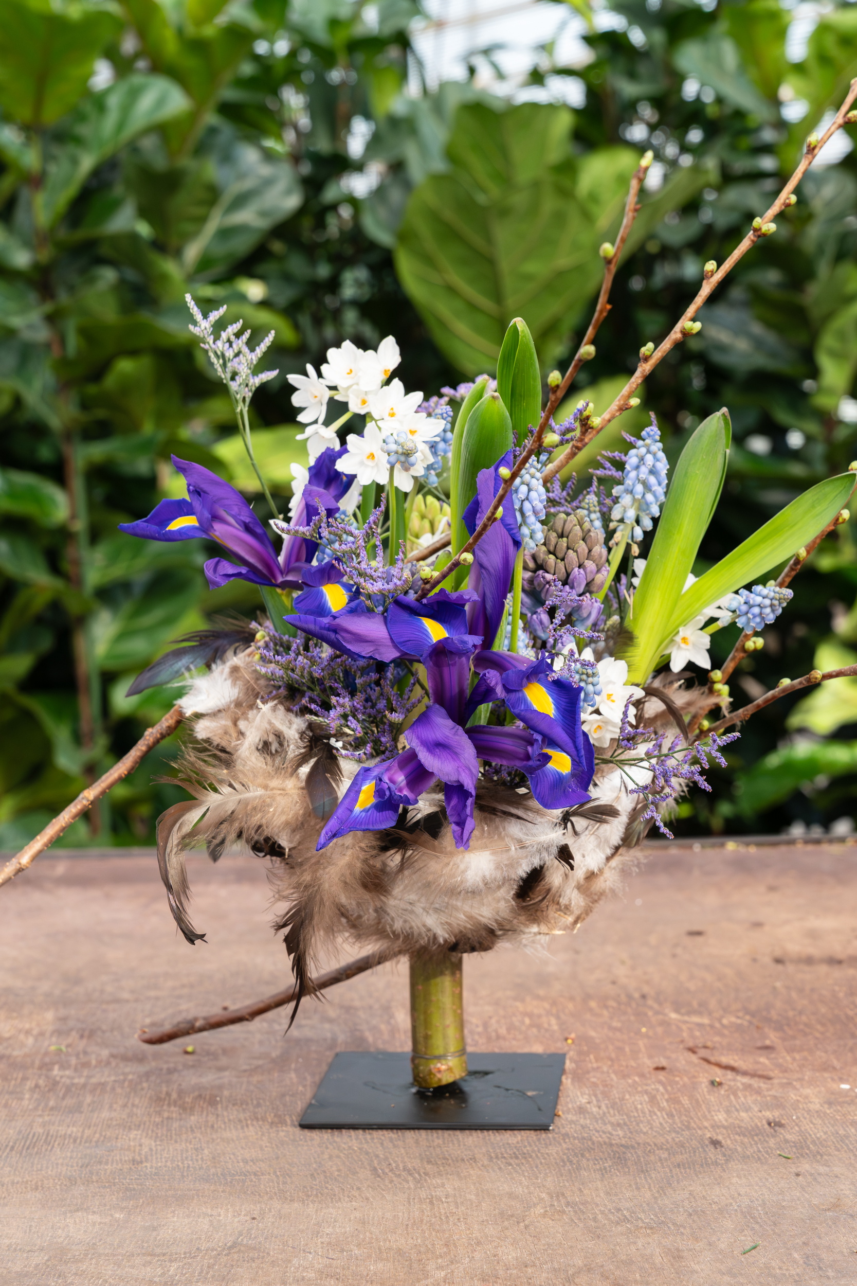 Boeket met paarse en witte bloemen in een vaas op tafel, groene achtergrond.
