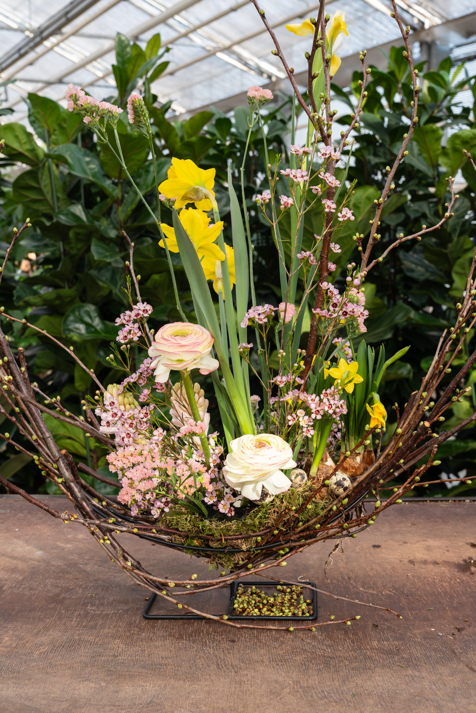 Bloemstuk met witte en gele bloemen in halvemaanvorm, in een kas