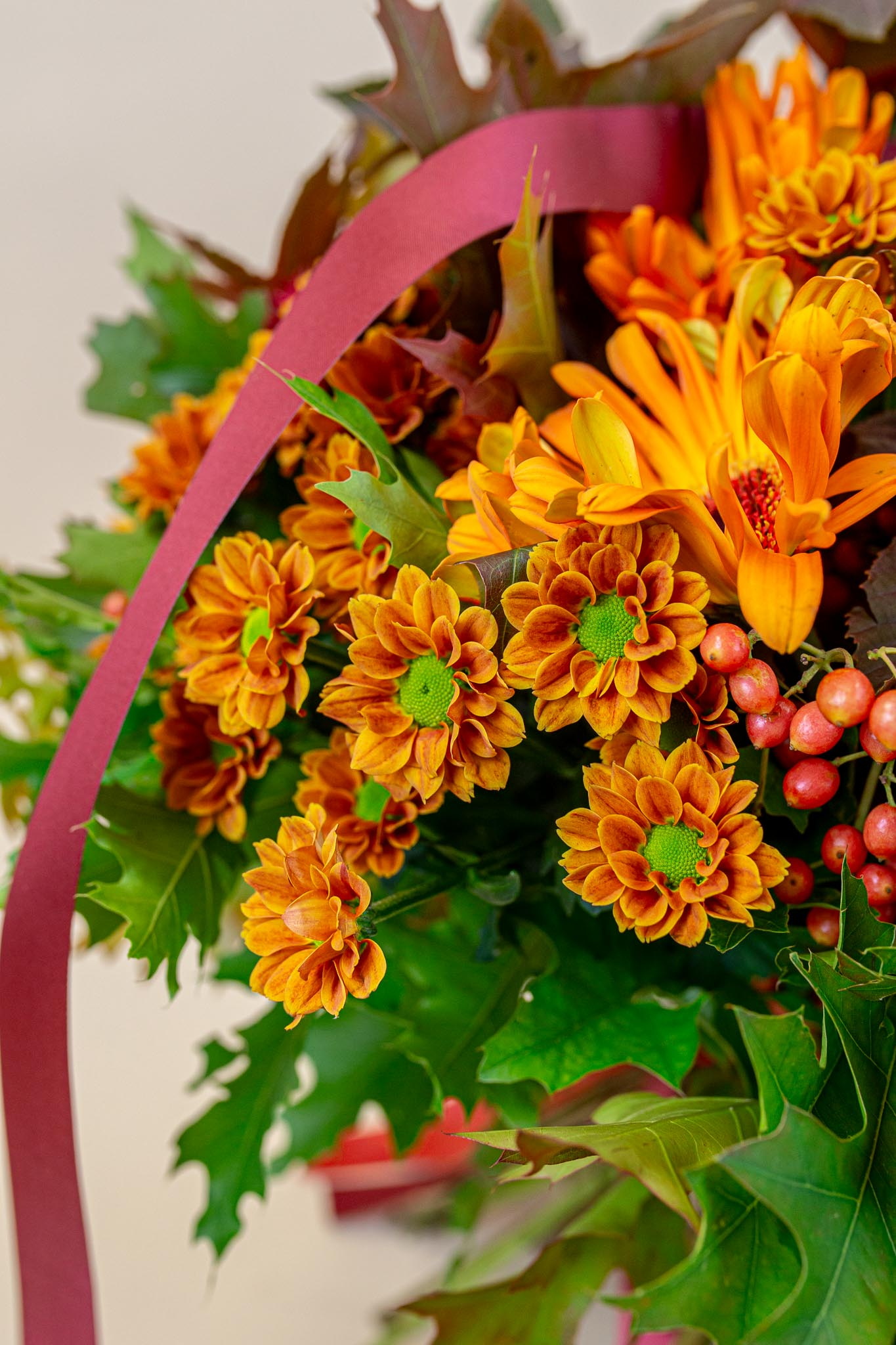 Boeket met oranje bloemen, groene bladeren en roze lint op witte achtergrond