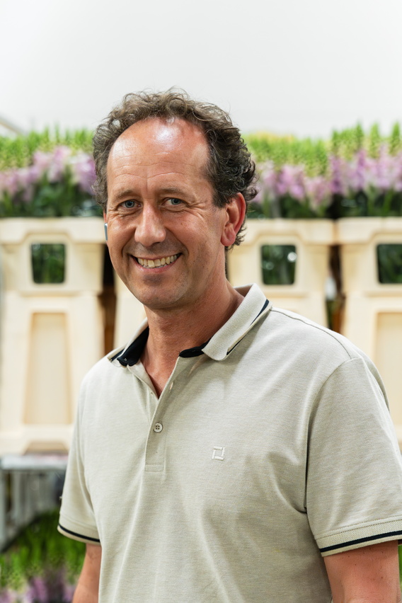 Lachende man in lichtgroen poloshirt voor bloemenrekken in tuincentrum