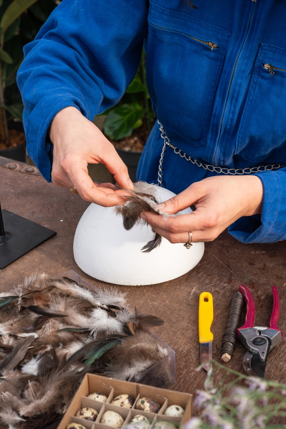 Handen strippen veren van een vogel op tafel met gereedschap en witte schaal.