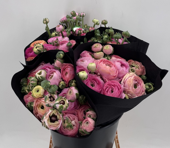monobos met roze ranonkels en groen, omwikkeld met zwart papier.