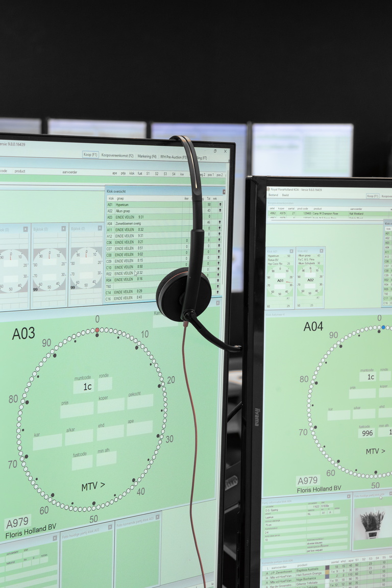 Twee computerschermen met groene dataweergave en een koptelefoon ertussen