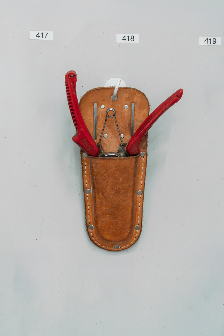 Bruine leren holster met rode gereedschapstangen en een metalen clip op witte achtergrond