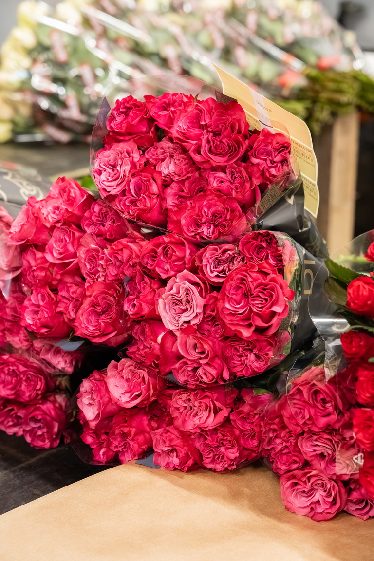 Bos felroze rozen op een tafel, met andere bloemen op de achtergrond.