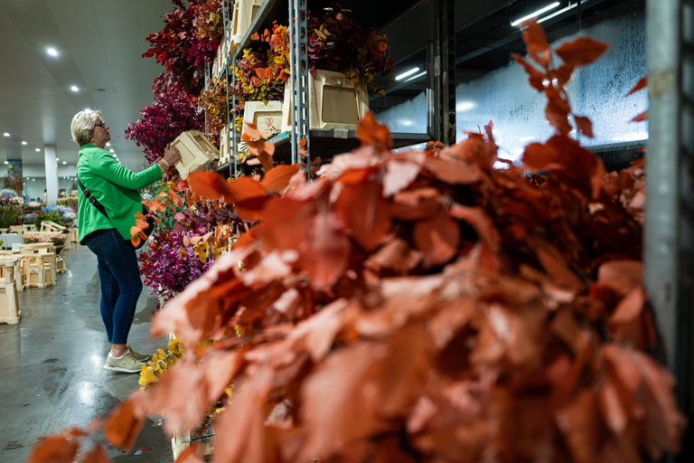 Grote hoop oranje bladeren in kas; persoon in groene jas werkt op de achtergrond.