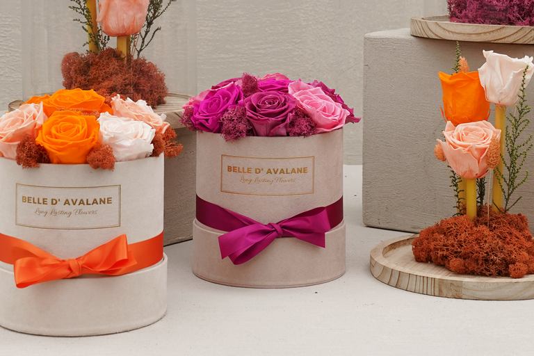 Drie ronde bloemendozen met rozen en gekleurde strikken op tafel