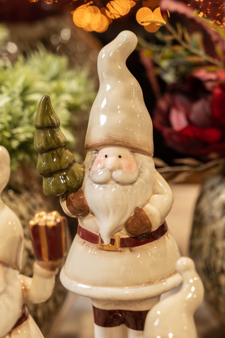 Kerstmanbeeldje met wit pak en puntmuts, warm verlichte kerstdecoratie op achtergrond