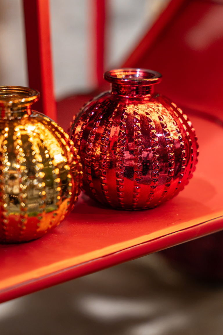 Twee glanzende decoratieballen op rode plank, goud en rood in de voorgrond