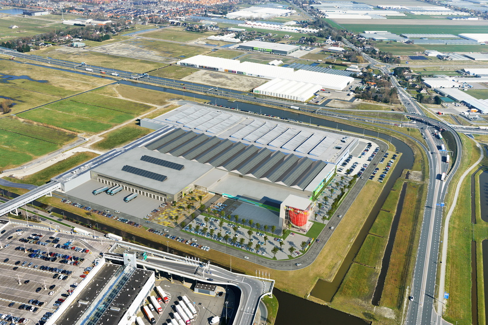 Luchtfoto van groot industriecomplex met parkeerplaatsen en omringende weilanden