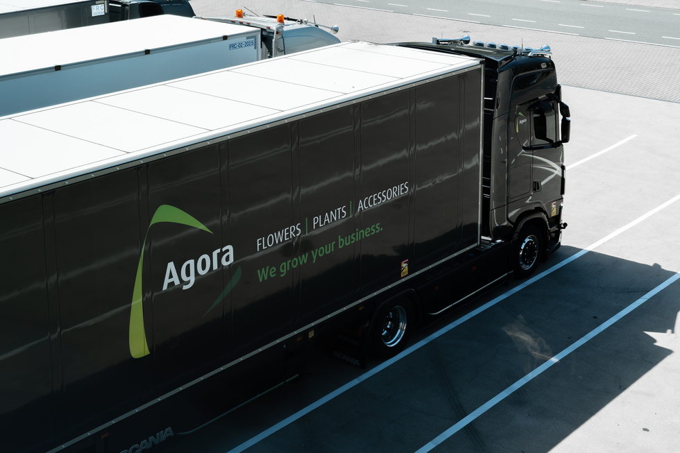 Zwarte vrachtwagen met Agora-logo geparkeerd op een parkeerplaats van bovenaf