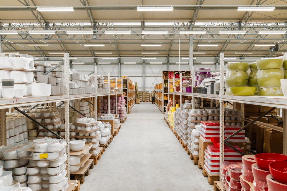 Gangpad in magazijn met rekken vol servies en gekleurde emmers